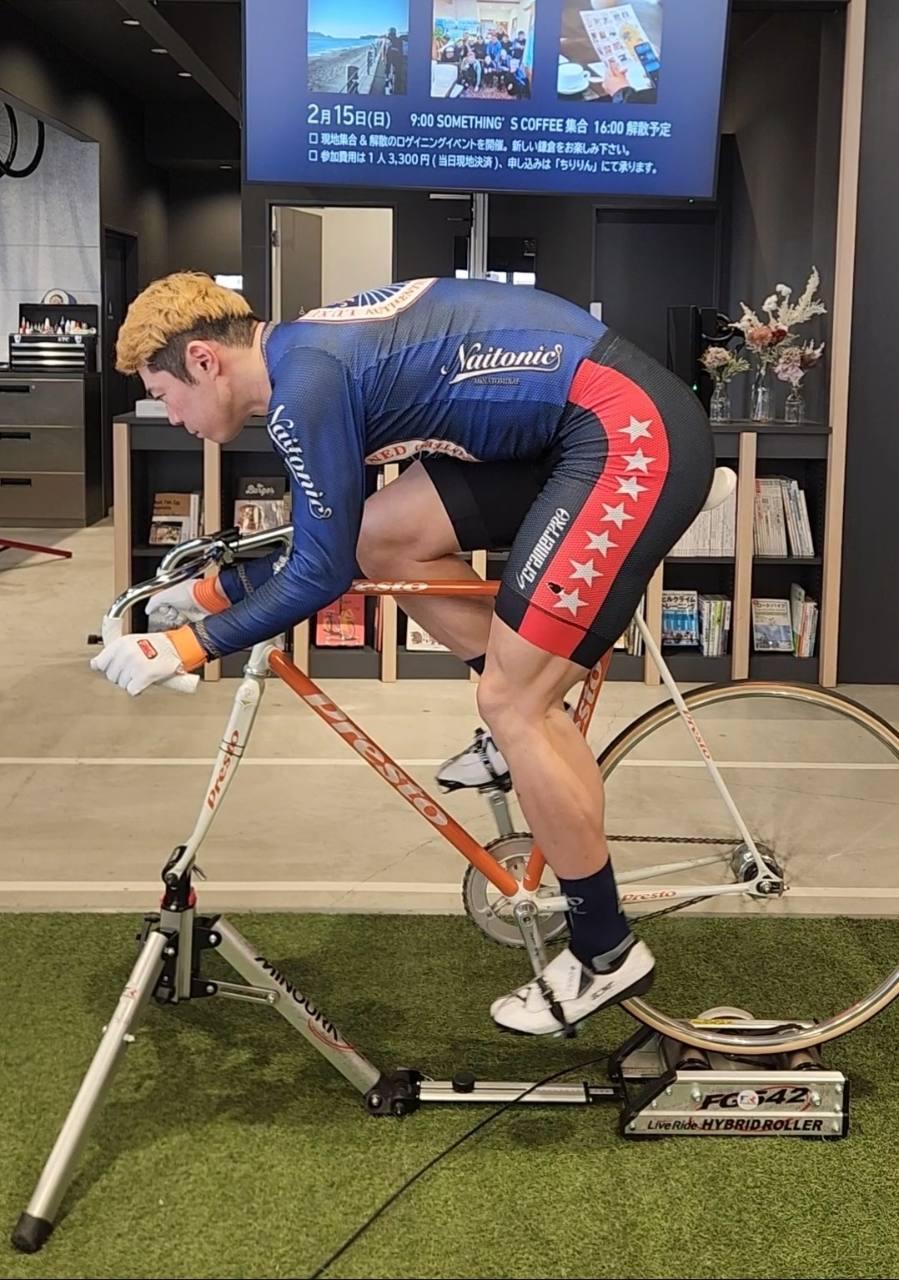 ローラー台に固定したオレンジ色の競輪自転車で乗車姿勢を確認する様子